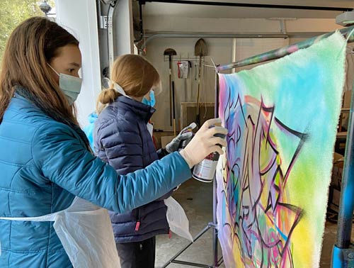 girl using spray paint onto canvas