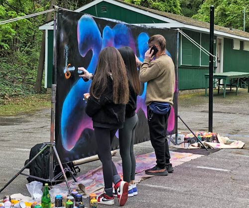 2 girls spraying onto a canvas