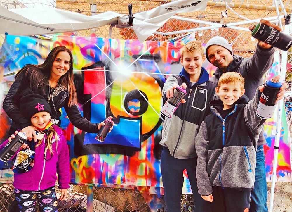 Adults and children holding spray paint while smiling