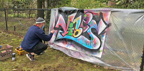 man spray painting onto canvas