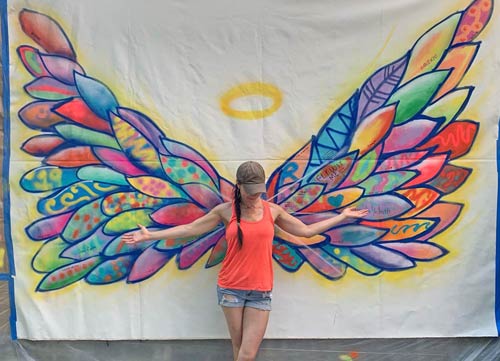woman posing in front of wing artwork