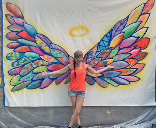 woman posing in front of graffiti wings
