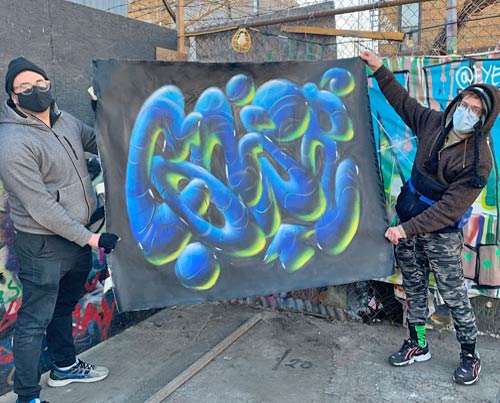 2 men holding up a canvas artwork