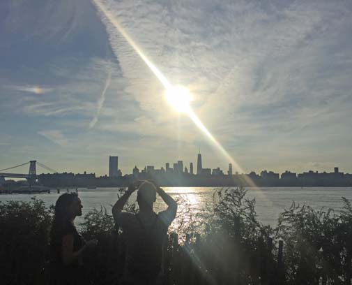 man taking photo of sunset over NYC
