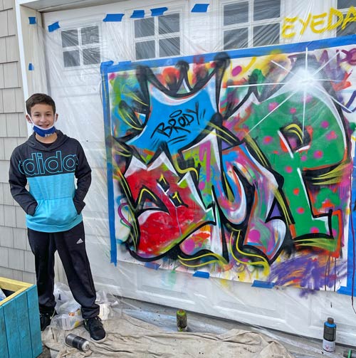 boy posing next to a canvas artwork